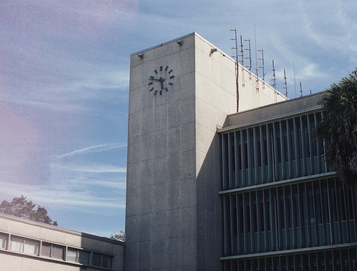 brutalist building with giant clock tower under clear sky