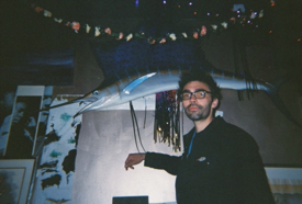 stylish man standing in front of fake wall-mounted marlin